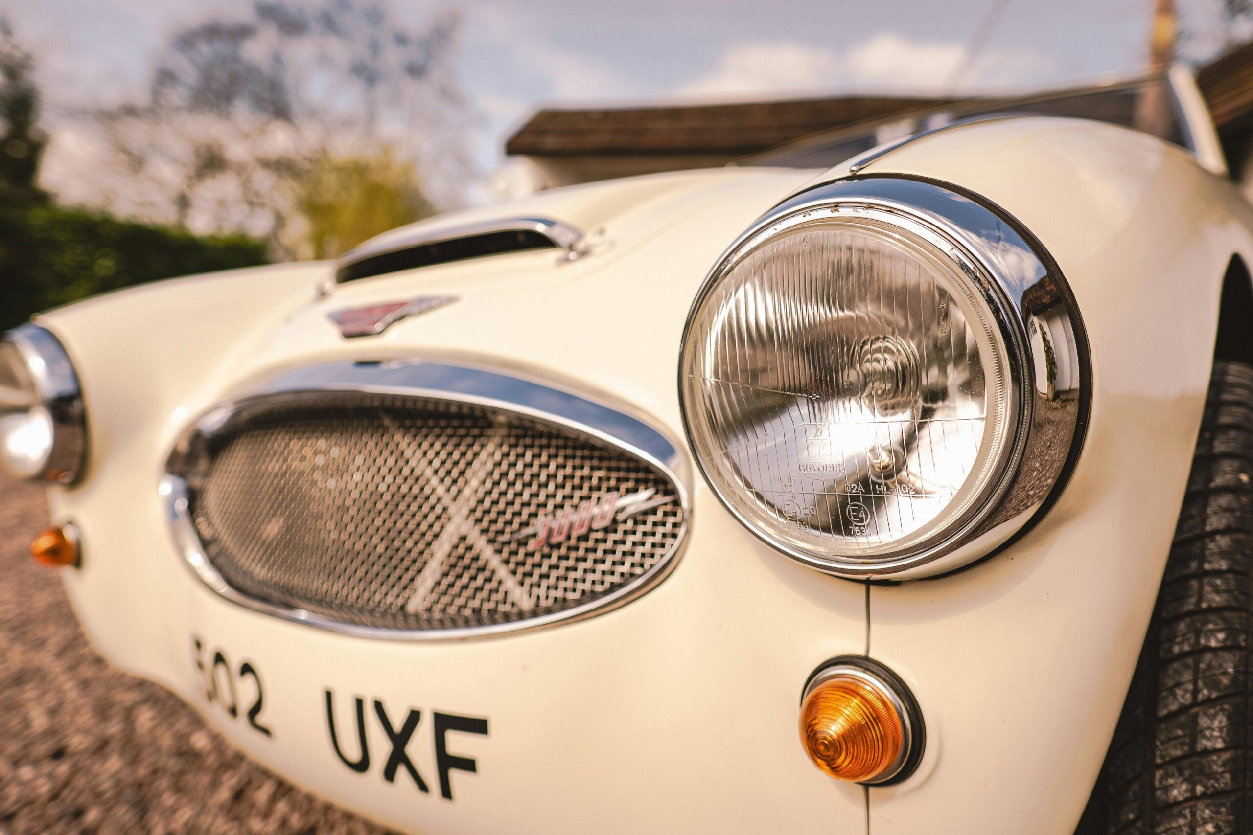 Detailansicht des Scheinwerfers eines Austin Healey, der seinen Vintage-Charme zur Geltung bringt.