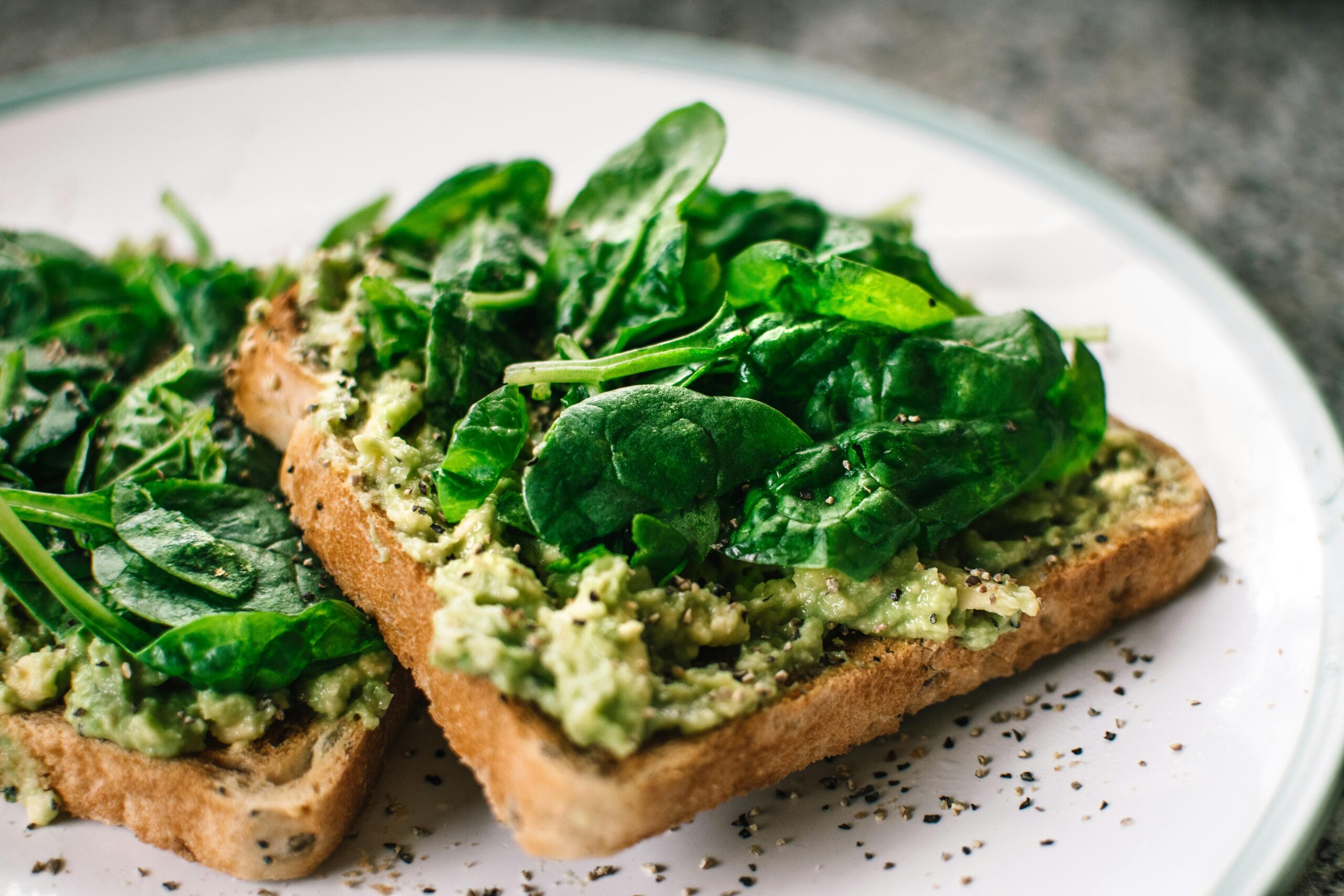 BasilikumblÃ¤tter Und Avocado Auf Geschnittenem Brot Auf WeiÃŸer Keramikplatte