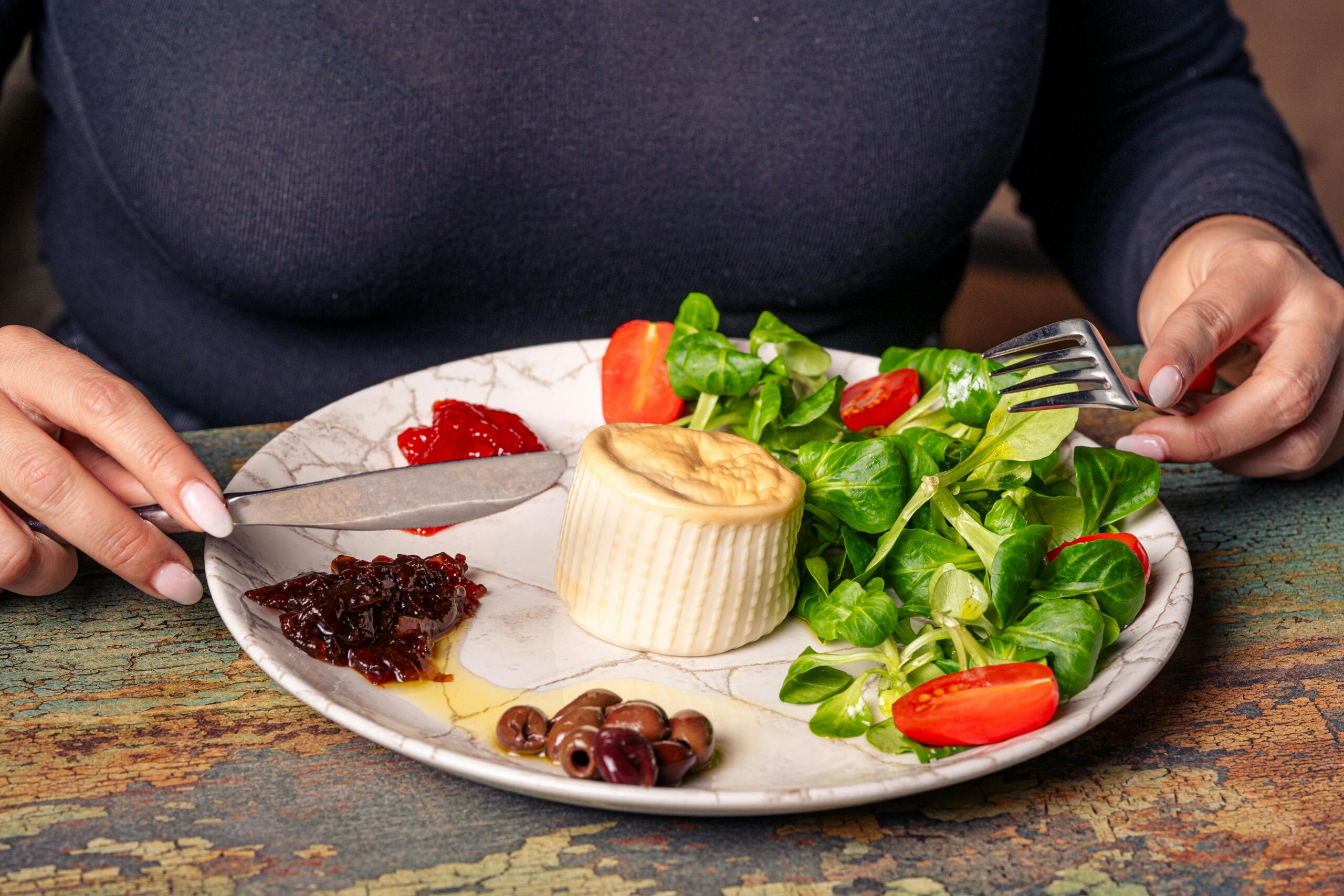 KÃ¶stlicher Gourmetsalat mit frischem GrÃ¼n, KÃ¤se, Oliven und Tomaten auf einem rustikalen Teller.