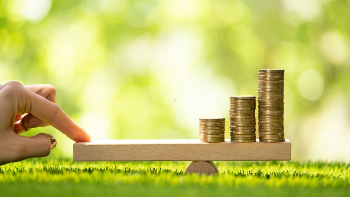 Drei Hartgeld Stabel auf einer Waage mit eine Hand der die Waage ausgleicht